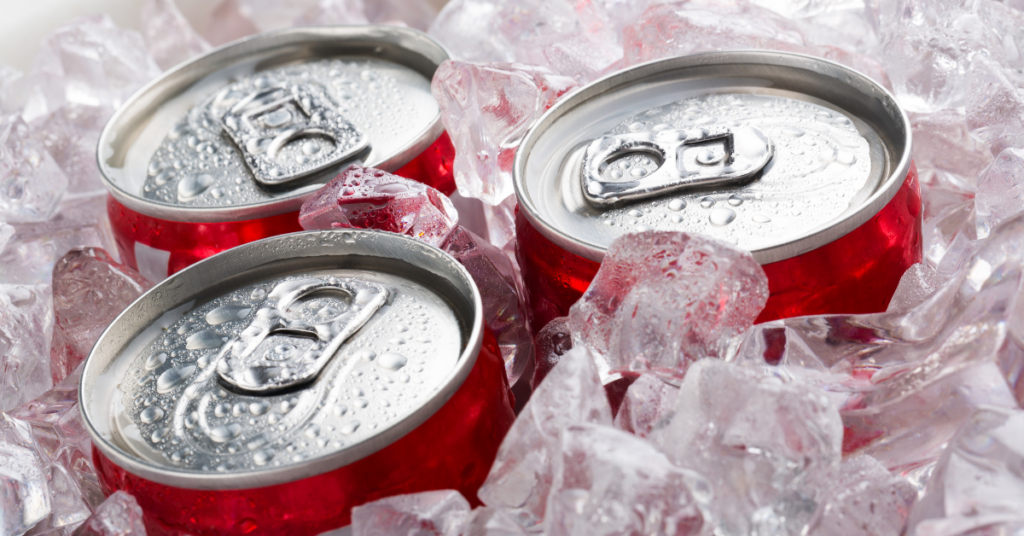Three cans of coca cola sitting on ice.